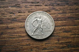 Pièce d'argent 50 francs 1977 avec Hercule posée sur un bureau en bois foncé, vue macro détaillée