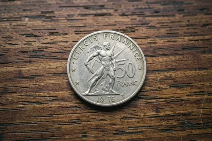 Pièce d'argent 50 francs 1977 avec Hercule posée sur un bureau en bois foncé, vue macro détaillée